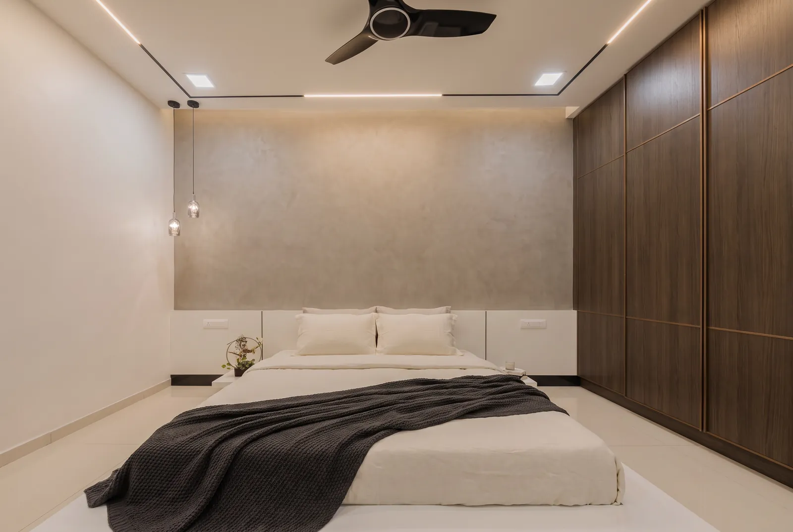 A calm bedroom with a full-height smoked-oak wardrobe with fine bronze lines.